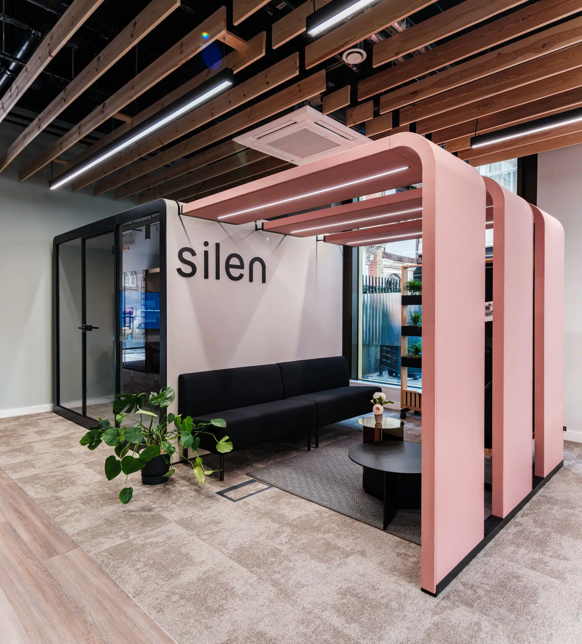 Silen Bridges Connect in shrimp, an open overhead frame with LED strips, set over a seating area